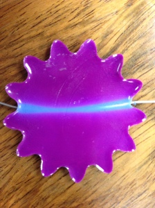 Shape memory polymer with Rubine Red Solar Color Dust and Blue Casting Craft Dye.  A nichrome wire has been incorporated into the polymer.  Here, the wire has been heated.  As you can see, the heat concentration has caused the powder to become white and allowed the blue dye to show through.